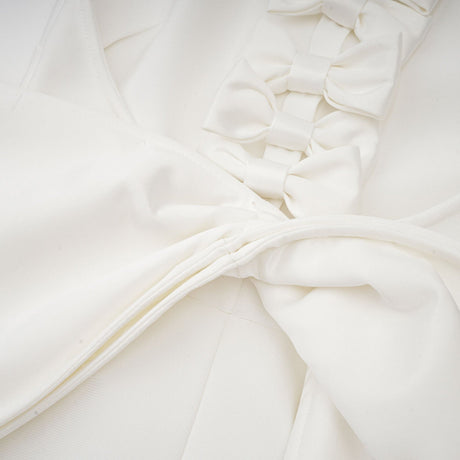 A white bandage dress with an oversized bow detail featuring a fitted silhouette and a capucine style design