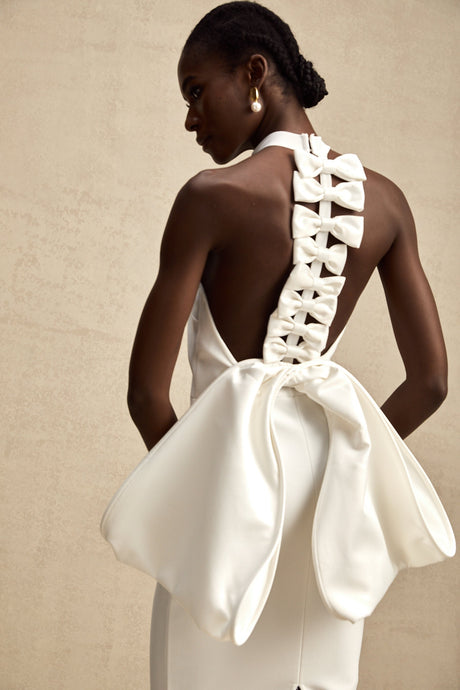 A white bandage dress with an oversized bow detail featuring a fitted silhouette and called Capucine
