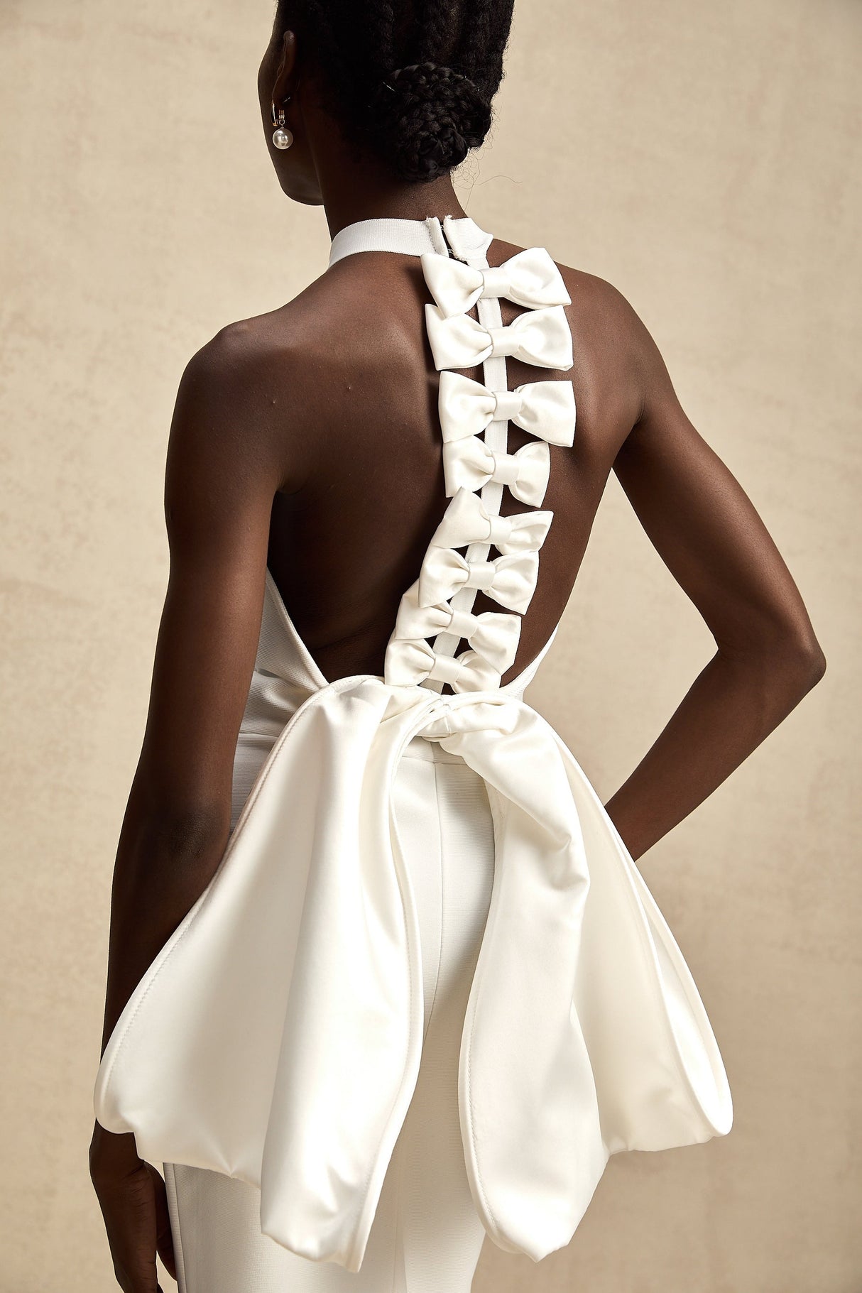 A white bandage dress with an oversized bow detail featuring a fitted silhouette and capucine style design