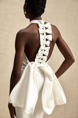 A white bandage dress with an oversized bow detail featuring a fitted silhouette and capucine style design