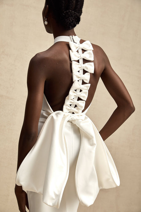 A white bandage dress with an oversized bow detail featuring a fitted silhouette and capucine style design