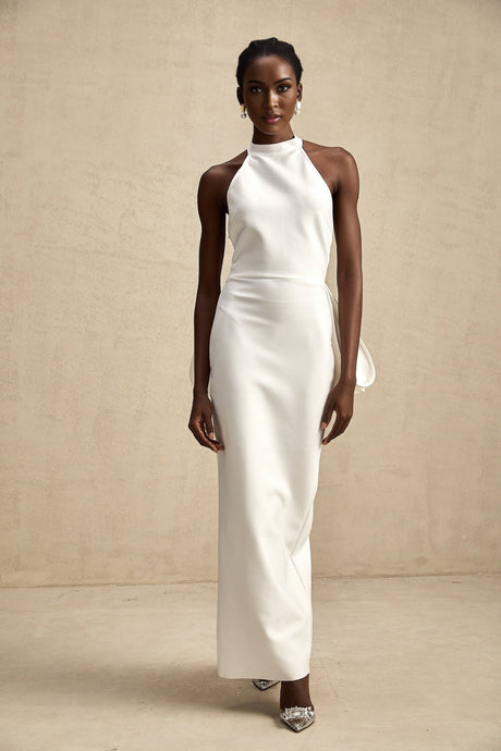 A white bandage dress with an oversized bow detail featuring a formfitting silhouette and a capucine style design