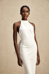 A white bandage dress with an oversized bow detail named Capucine featuring a fitted silhouette and exaggerated bow accent