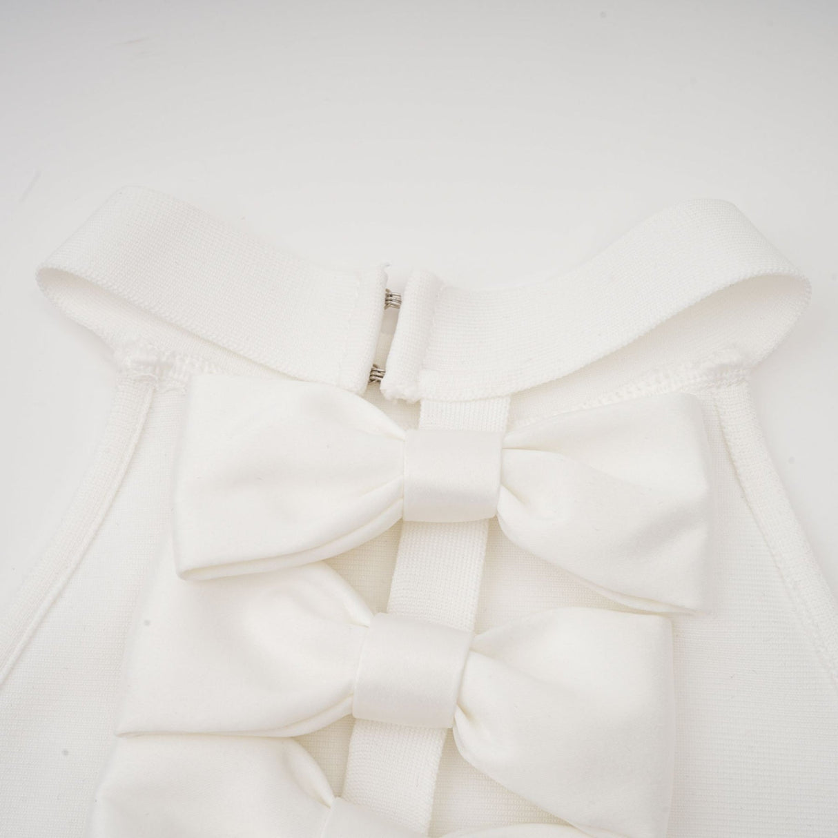 A white bandage dress with an oversized bow detail named Capucine featuring a formfitting silhouette and elegant design
