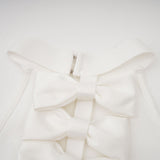 A white bandage dress with an oversized bow detail named Capucine featuring a formfitting silhouette and elegant design