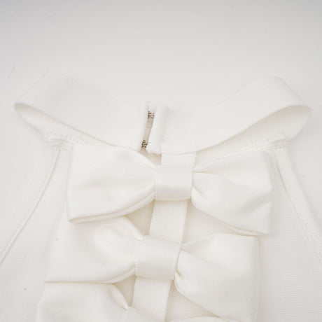 A white bandage dress with an oversized bow detail named Capucine featuring a formfitting silhouette and elegant design