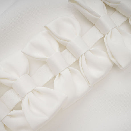 A white bandage dress with an oversized bow detail named Capucine featuring a formfitting silhouette and exaggerated bow accent