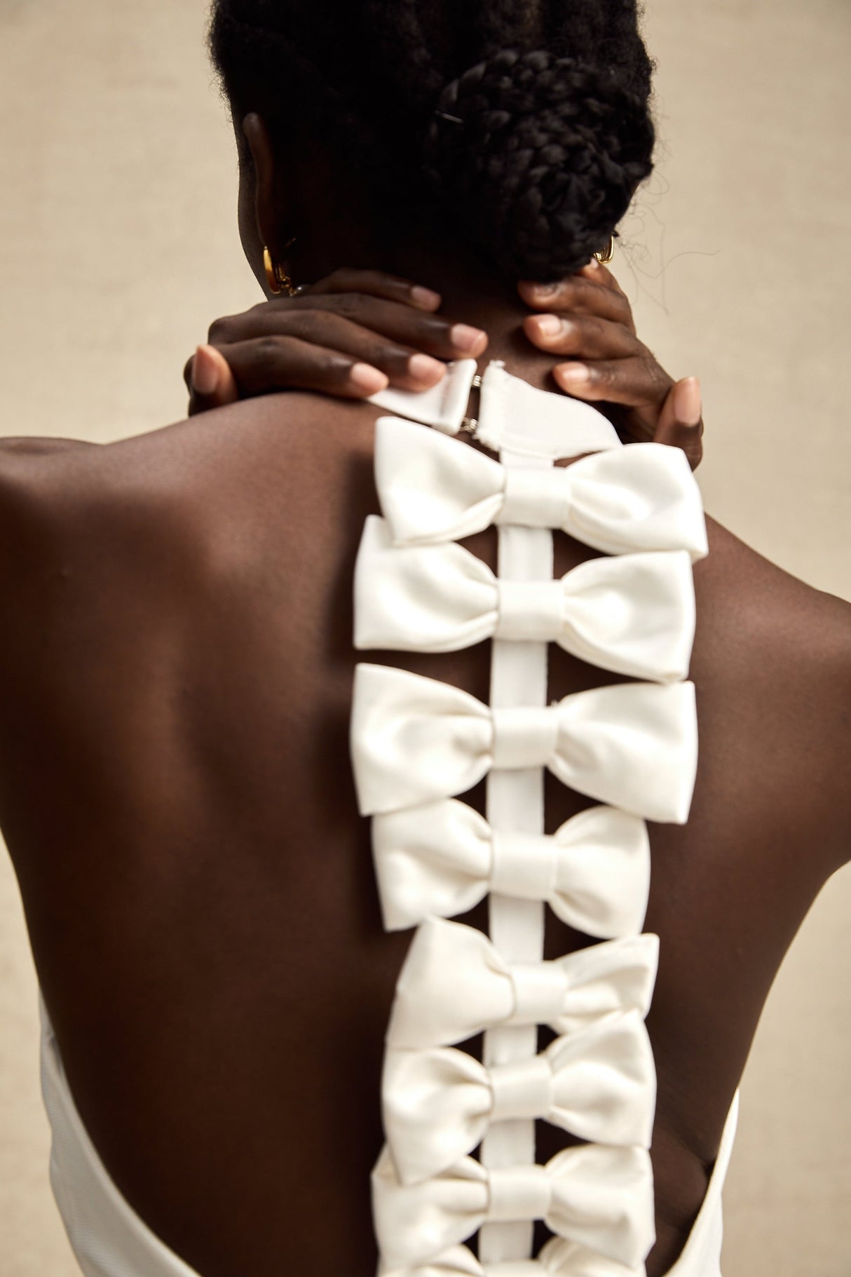 A white bandage dress with an oversized bow detail named Capucine featuring a formfitting silhouette and sleeveless design