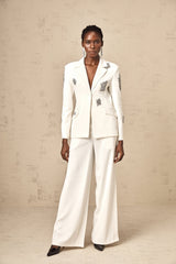 A white blazer and trouser set embellished with crystal details featuring a tailored jacket and matching pants