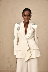 A white blazer and trouser set with butterfly applique embellishments The blazer features long sleeves and a tailored fit while the trousers are straight leg Both pieces are adorned with delicate white butterfly decorations creating an elegant and whimsical look