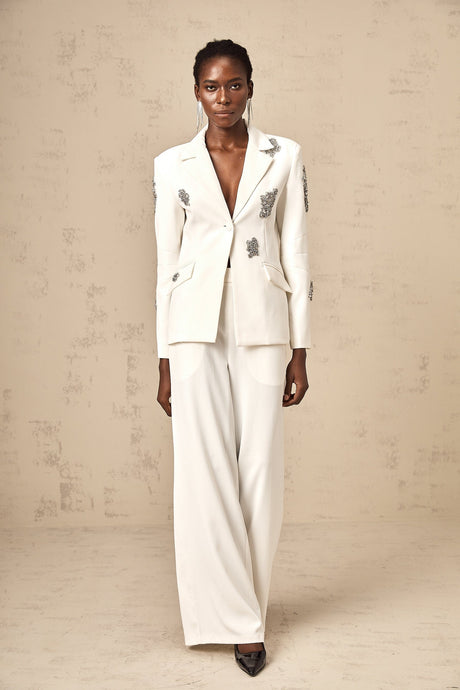 A white blazer and trousers set adorned with crystal embellishments featuring a tailored silhouette and matching design