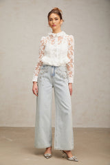 A white blouse with delicate floral embroidery and lace detailing named Karine