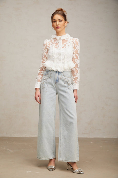 A white blouse with delicate floral embroidery and lace detailing named Karine