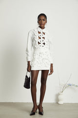 A white buttonup shirt with floral cutout patterns and short sleeves featuring a collar and relaxed fit