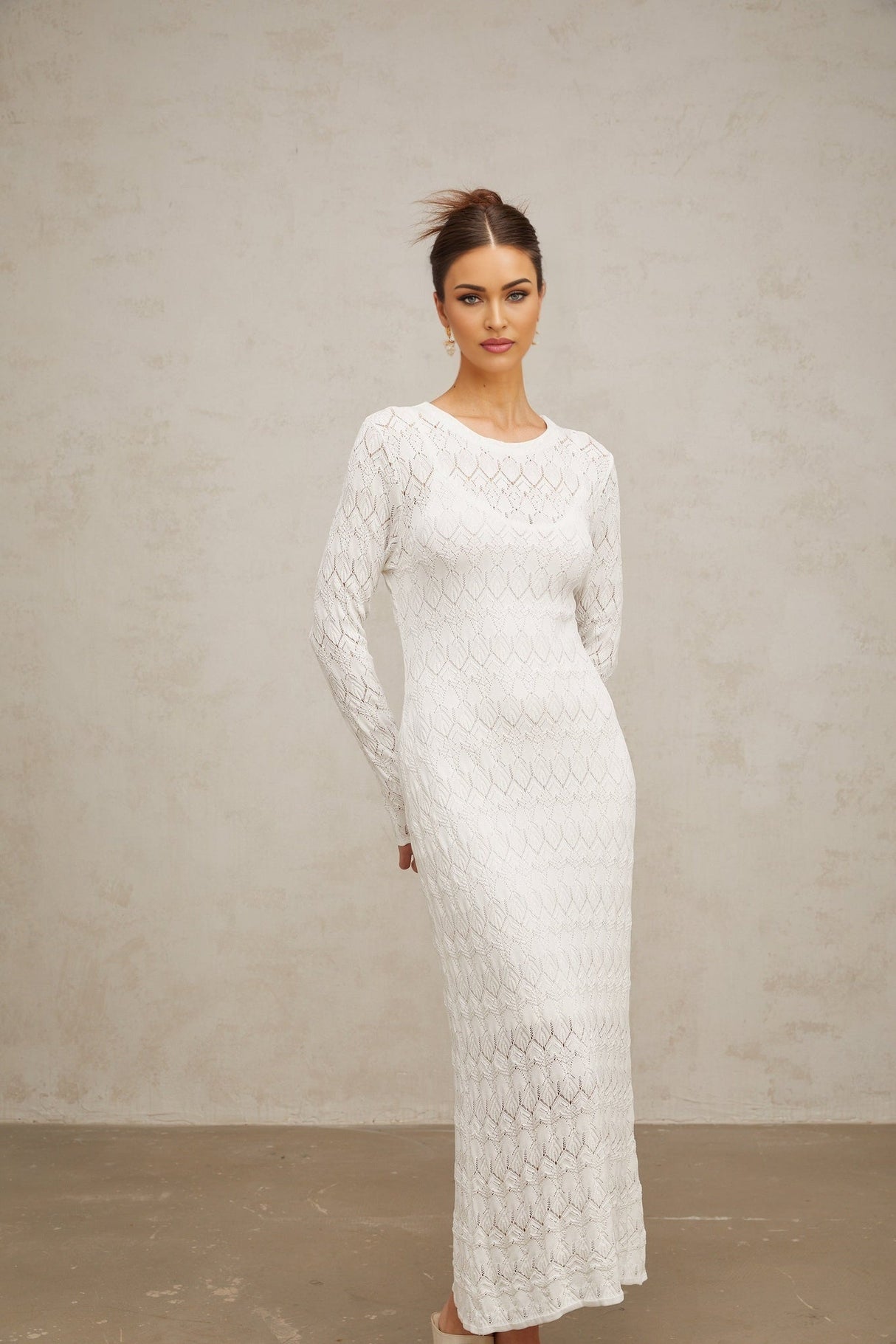A white crochet knit midi dress with a flowing silhouette and intricate lace pattern