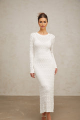 A white crochet knit midi dress with intricate lace patterns hanging on display