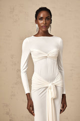 A white floorlength maxi dress with ruched fabric and a ribbon twist detail