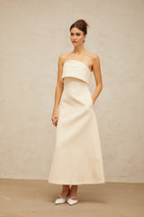 A white folded corset midi dress with a fitted bodice and flared skirt hanging on display