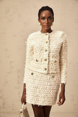 A white furry knit cardigan and matching skirt set on a plain background showcasing a cozy winter outfit combination