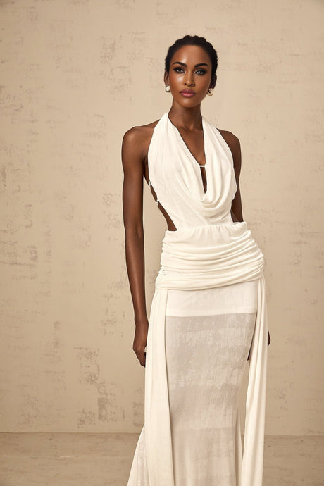 A white halterneck maxi dress with a backless design featuring a long flowing skirt and open back detail