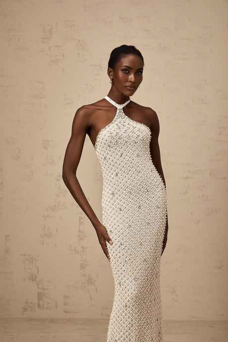A white halterneck maxi dress with embellishments named Claudine featuring a long flowing skirt and decorative details on the bodice