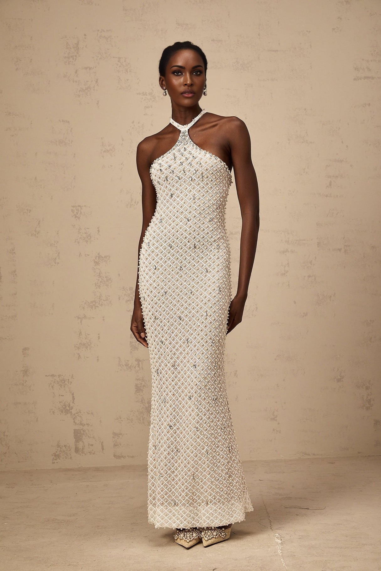 A white halterneck maxi dress with embellishments named Claudine featuring a long flowing skirt and sleeveless design