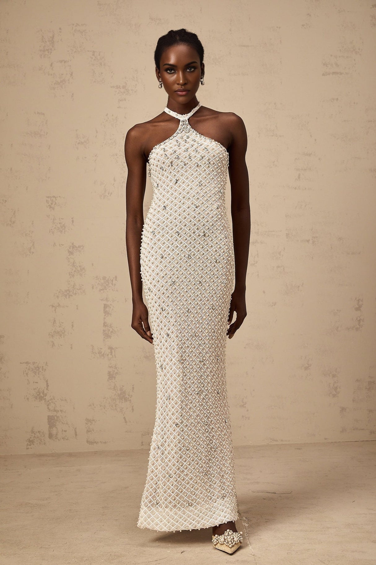 A white halterneck maxi dress with embellishments named Claudine featuring a long flowing skirt and sleeveless design