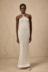 A white halterneck maxi dress with embellishments named Claudine featuring a long flowing skirt and sleeveless design