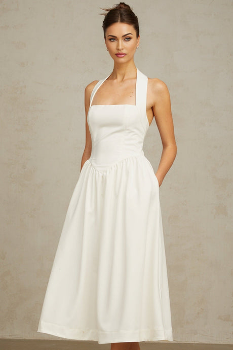 A white halterneck midi dress with pleated details and a fitted silhouette worn by a model against a plain background