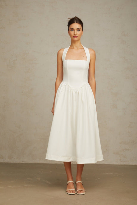 A white halterneck midi dress with pleated details and a fitted waistline on a female model