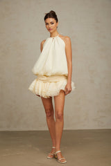 A white halterneck mini dress with faux pearl embellishments on a female model