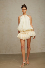 A white halterneck mini dress with faux pearl embellishments on a female model