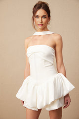A white halterneck mini dress with ruffled details modeled on a female figure against a plain background
