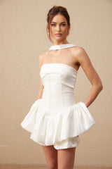 A white halterneck mini dress with ruffled details named Olivia worn by a model standing against a plain background