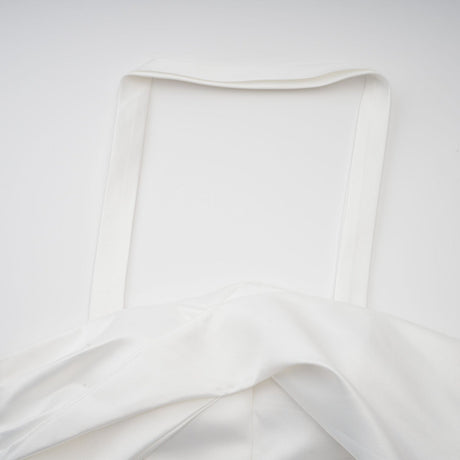 A white halterneck mini dress with ruffled details worn by a model named Olivia featuring a sleeveless design and a short hemline