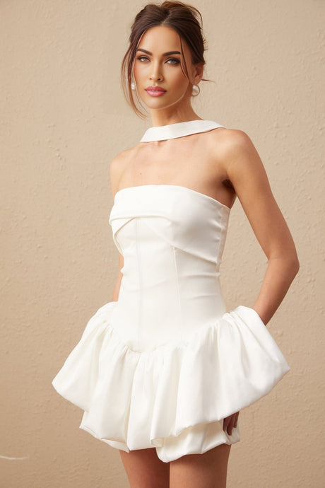 A white halterneck mini dress with ruffled details worn by a model named Olivia standing against a plain background