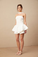 A white halterneck mini dress with ruffled details worn by a model named Olivia