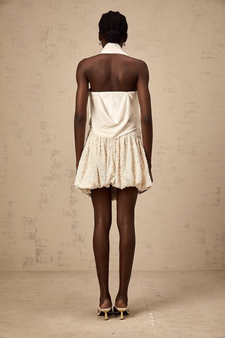 A white halterneck top with floral appliques featuring a sleeveless design and delicate floral embellishments on the fabric