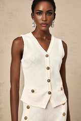 A white knitted matching set featuring a top and trousers worn by a model standing against a plain background