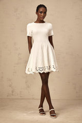 A white knitted mini dress with cut out jacquard detailing worn by a model named Emilie