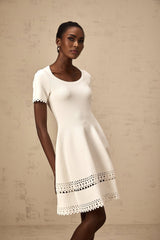 A white knitted mini dress with cutout details featuring a floral pattern and a short hemline