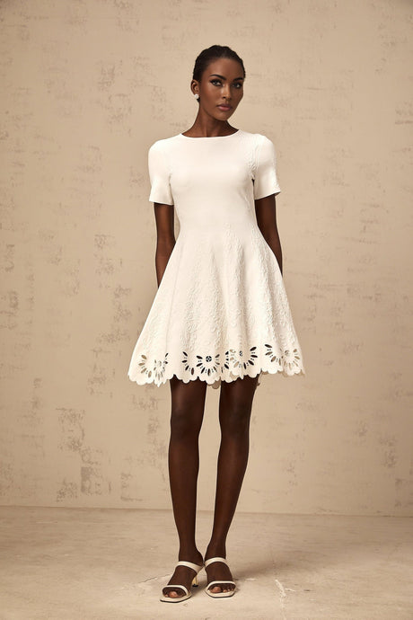 A white knitted mini dress with jacquard pattern and cut out details worn by a model named Emilie