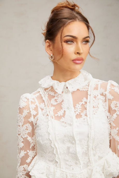 A white lace blouse with floral embroidery patterns featuring a delicate feminine design named Karine