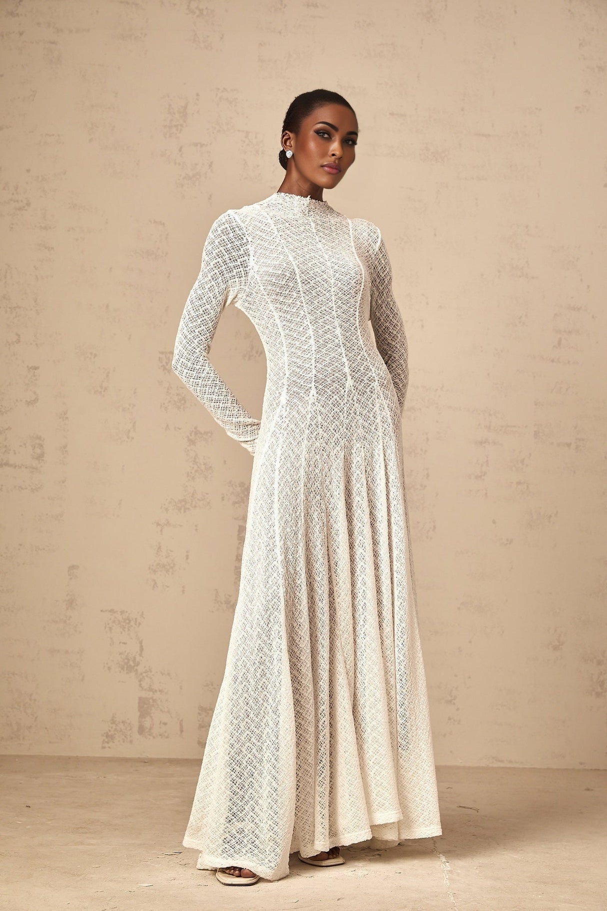 A white lace maxi dress with a wavy pattern design and long flowing silhouette