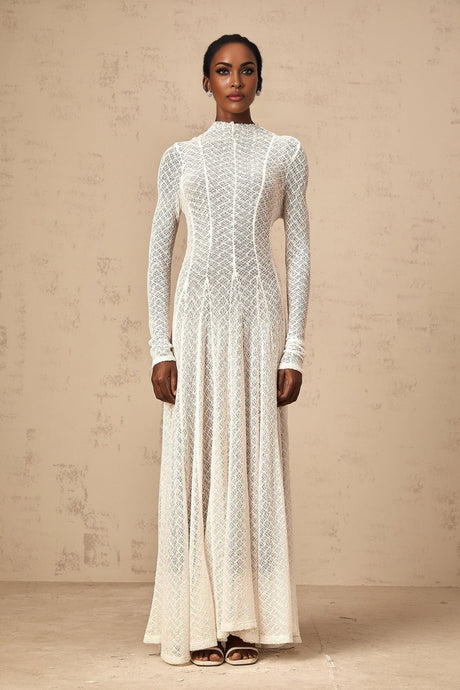 A white lace maxi dress with a wavy pattern design featuring long sleeves and a flowing skirt