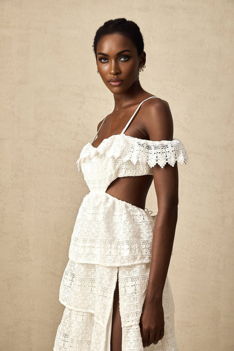 A white lace midi dress with an openwork pattern featuring delicate floral designs and a feminine silhouette