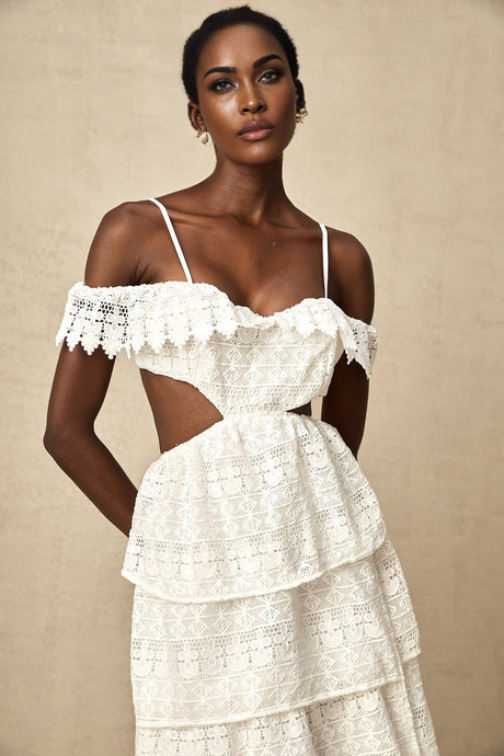 A white lace midi dress with openwork design and delicate floral patterns worn by a model standing against a plain background