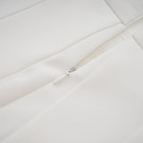 A white matching set consisting of a creased top and trousers worn by a model against a plain background