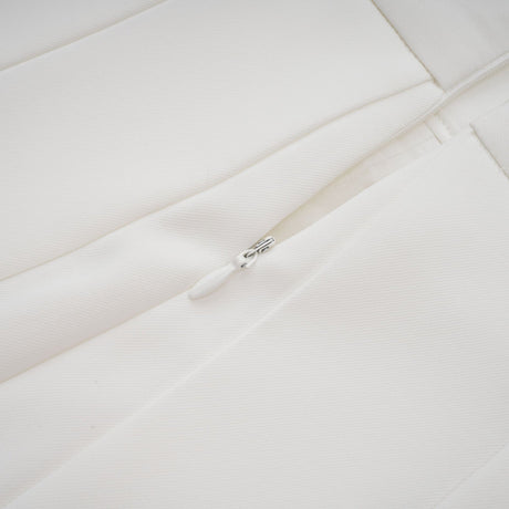 A white matching set consisting of a creased top and trousers worn by a model against a plain background