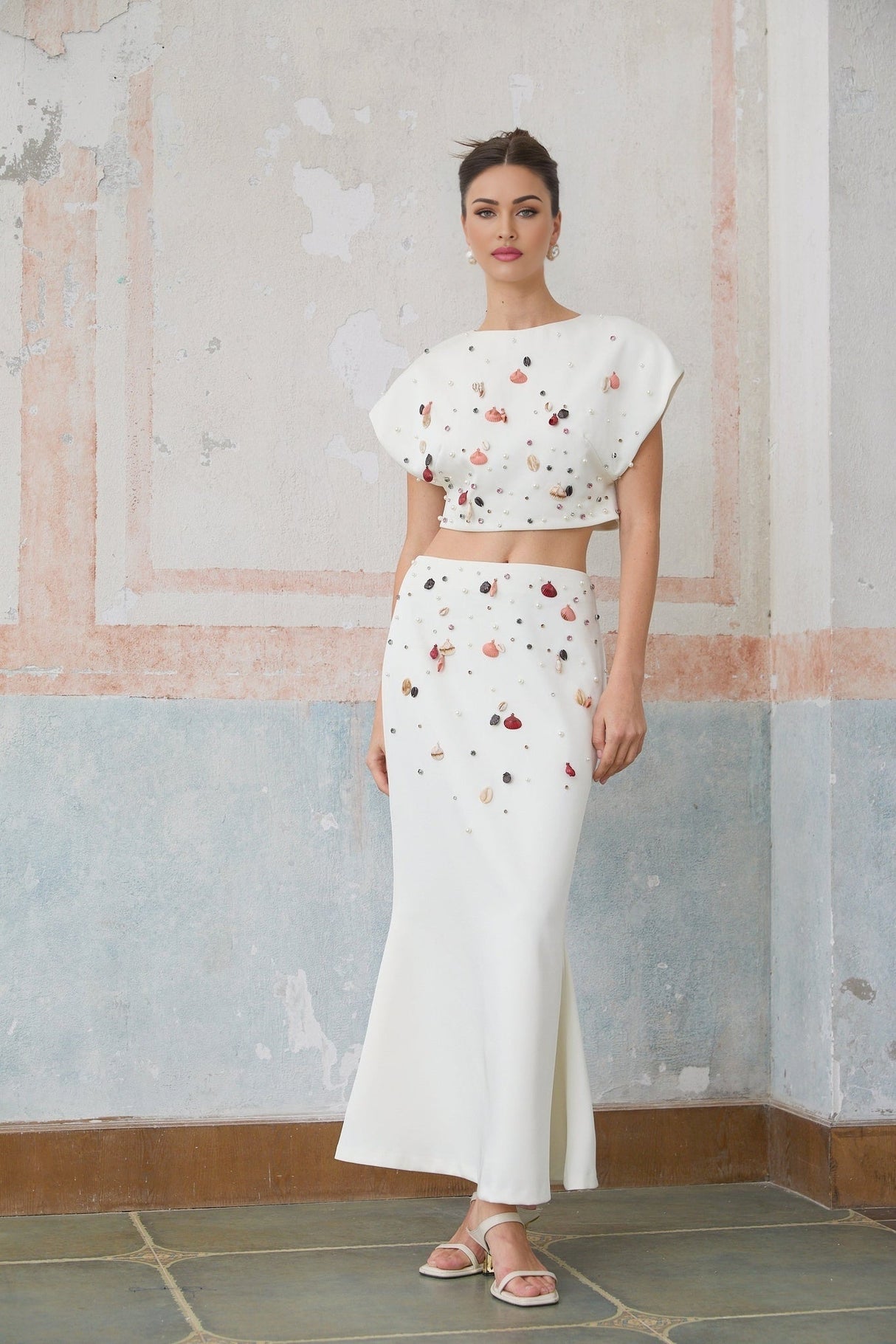 A white matching set consisting of a top and skirt adorned with shell embellishments featuring a design inspired by Delphine